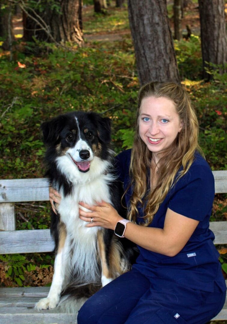 A woman holding a dog on the shoulder of another person.