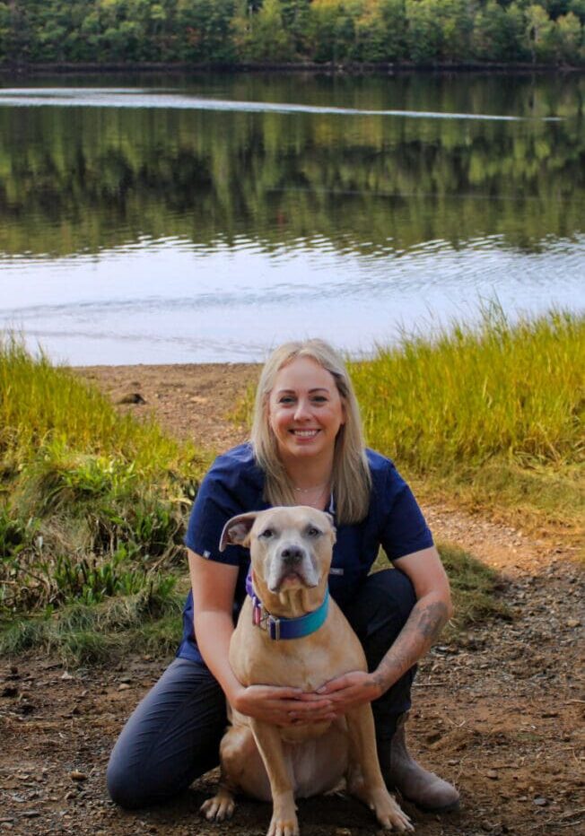 A woman sitting on the ground with her dog.